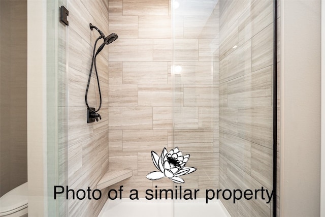 bathroom featuring toilet and a shower with door