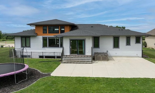 rear view of property featuring a yard, a patio, and a trampoline