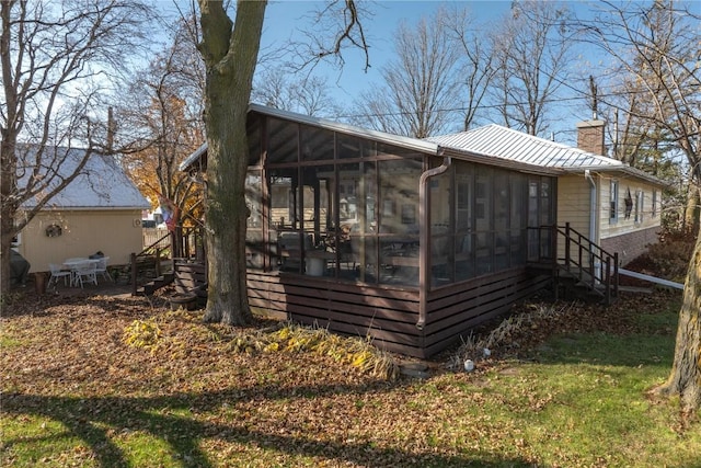 2482 65th St, Vinton, IA 52349 - view of property exterior featuring a chimney, a sunroom, and metal roof