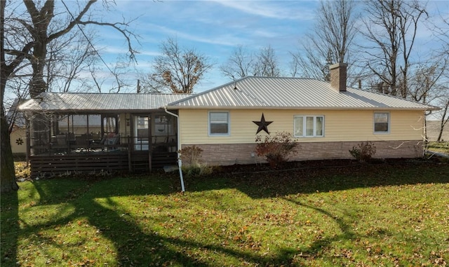2482 65th St, Vinton, IA 52349 - back of property with a chimney, a sunroom, a lawn, and metal roof