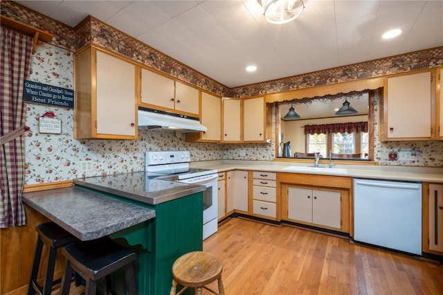 2482 65th St, Vinton, IA 52349 - kitchen featuring under cabinet range hood, white appliances, a sink, wallpapered walls, and light wood finished floors