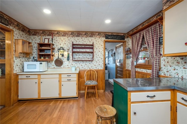 2482 65th St, Vinton, IA 52349 - kitchen with wallpapered walls, white microwave, stainless steel countertops, open shelves, and light wood finished floors