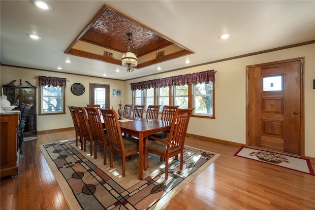 dining area featuring hardwood / wood-style floors, a raised ceiling, and a healthy amount of sunlight