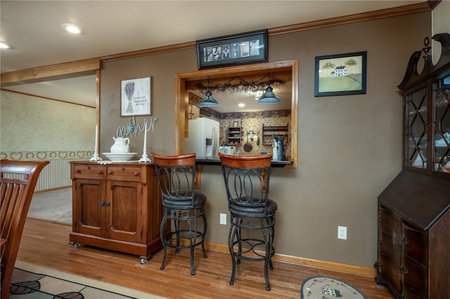 bar featuring light hardwood / wood-style floors, white fridge with ice dispenser, and crown molding