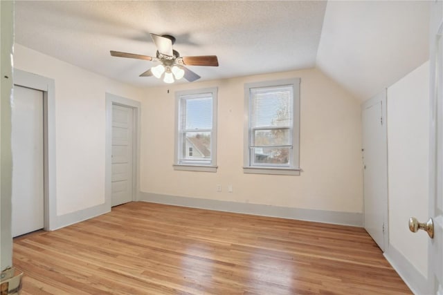 unfurnished bedroom featuring ceiling fan, vaulted ceiling, light hardwood / wood-style flooring, and a textured ceiling