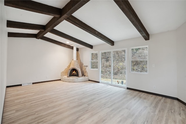 unfurnished living room with vaulted ceiling with beams, light hardwood / wood-style floors, and a fireplace