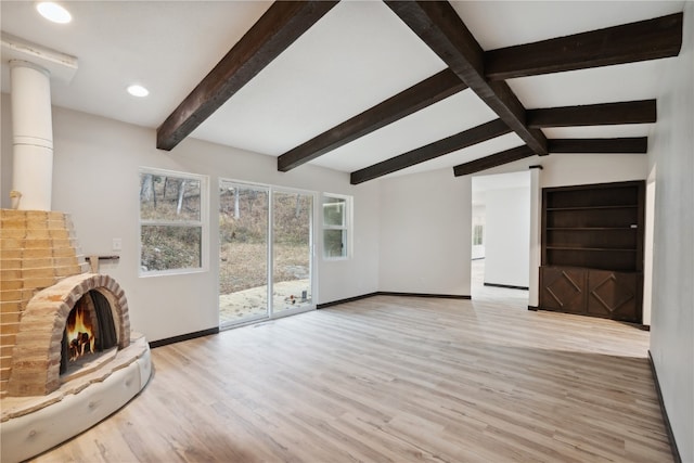 unfurnished living room featuring a brick fireplace, vaulted ceiling with beams, and light hardwood / wood-style flooring