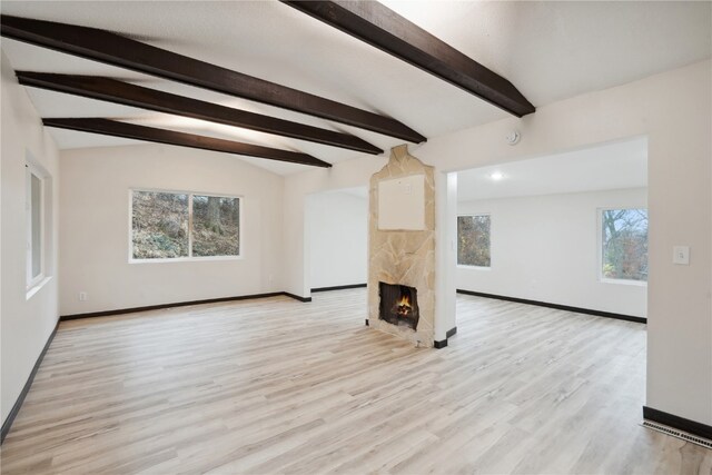 unfurnished living room with lofted ceiling with beams, light wood-type flooring, and a wealth of natural light