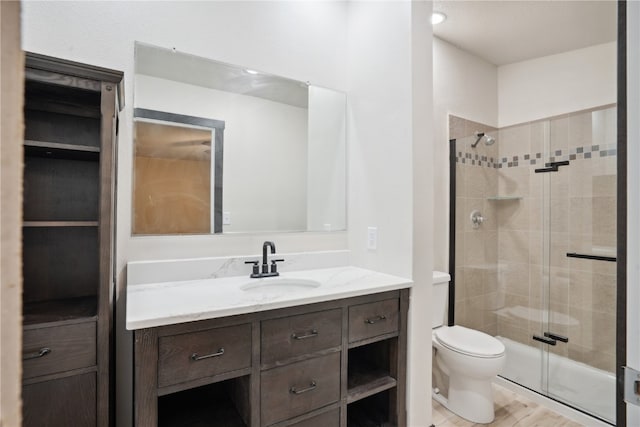 bathroom featuring vanity, hardwood / wood-style flooring, toilet, and a shower with shower door