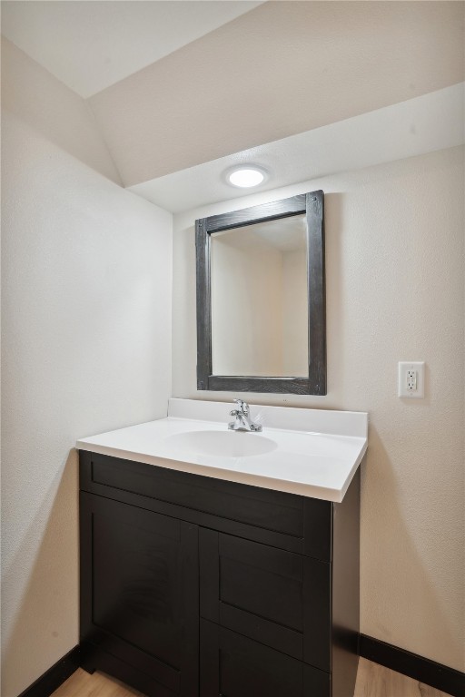 bathroom featuring vanity, vaulted ceiling, and hardwood / wood-style flooring