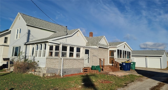 rear view of property with a garage and an outbuilding