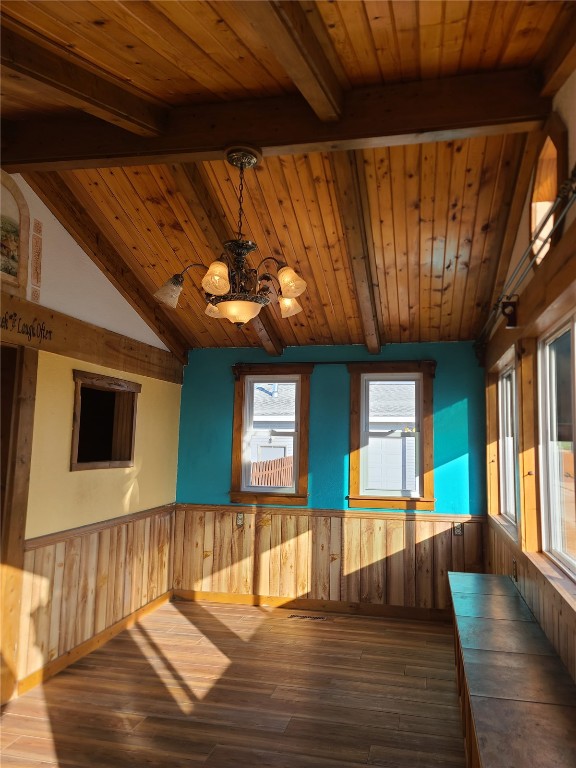 interior space featuring wooden ceiling, lofted ceiling with beams, wooden walls, hardwood / wood-style flooring, and a chandelier