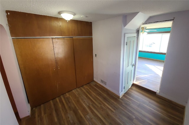 unfurnished bedroom featuring a textured ceiling, dark wood-type flooring, and a closet