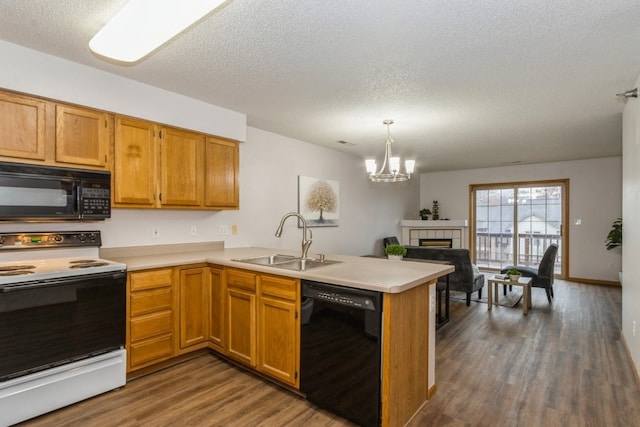 kitchen with a tile fireplace, sink, dark hardwood / wood-style floors, kitchen peninsula, and black appliances