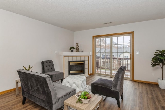 living room featuring a textured ceiling, wood-type flooring, and a fireplace