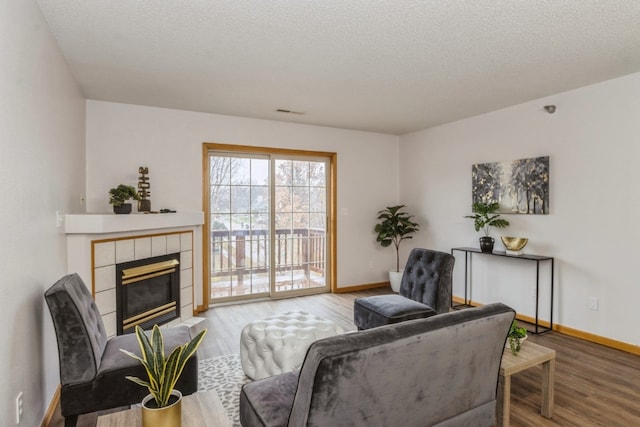 living room featuring a textured ceiling, light wood-type flooring, and a fireplace