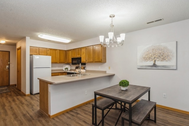 kitchen with kitchen peninsula, dark hardwood / wood-style flooring, white fridge, and decorative light fixtures