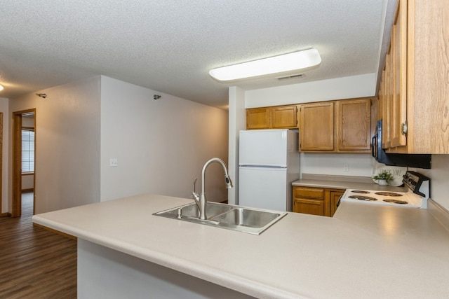 kitchen with sink, white appliances, kitchen peninsula, and dark wood-type flooring