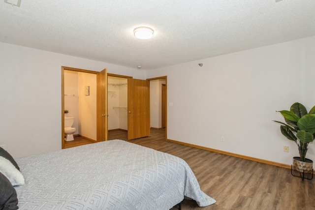 bedroom with hardwood / wood-style floors, a textured ceiling, and ensuite bath