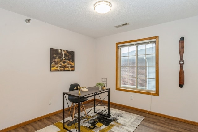 office with a textured ceiling and dark wood-type flooring