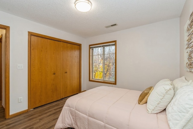 bedroom with a closet, dark hardwood / wood-style flooring, and a textured ceiling