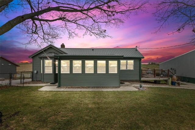 back house at dusk with a yard and a wooden deck