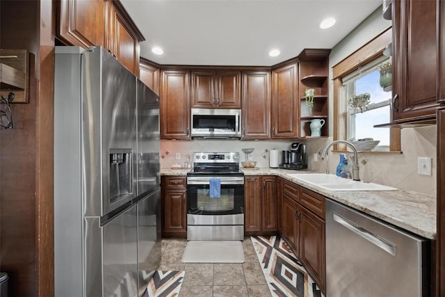 kitchen with appliances with stainless steel finishes, light stone countertops, sink, and decorative backsplash