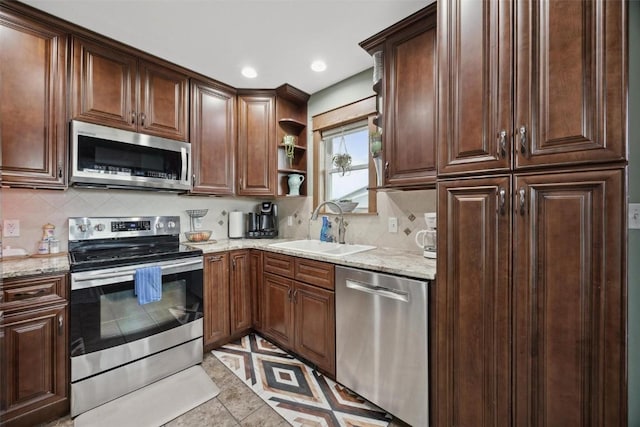 kitchen with stainless steel appliances, light stone countertops, sink, and decorative backsplash