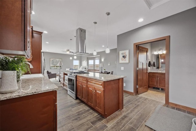 kitchen with appliances with stainless steel finishes, hanging light fixtures, hardwood / wood-style floors, a center island, and island exhaust hood