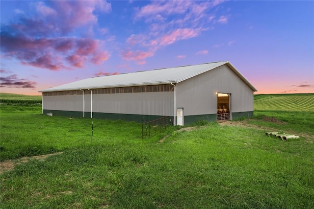 property exterior at dusk with a yard, an outbuilding, and a rural view