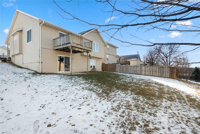 snow covered back of property with a balcony