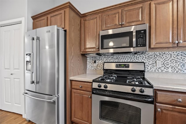 kitchen featuring decorative backsplash, light wood-type flooring, and stainless steel appliances