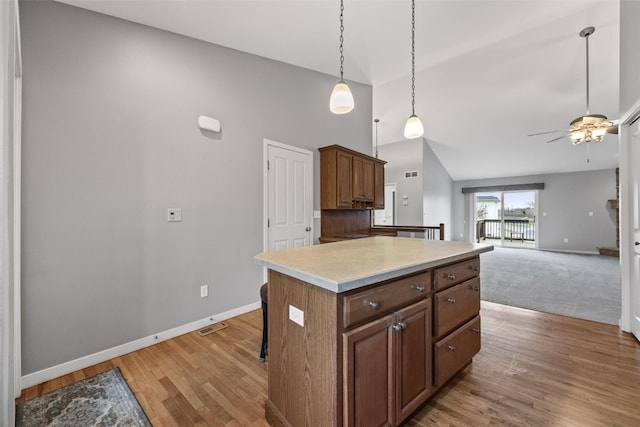 kitchen featuring pendant lighting, a center island, lofted ceiling, hardwood / wood-style flooring, and ceiling fan