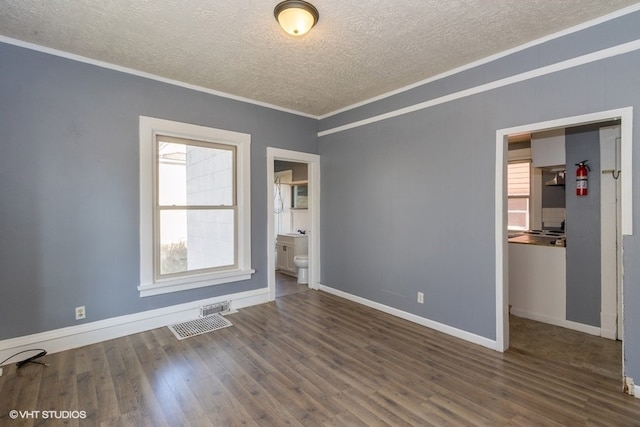 empty room featuring dark hardwood / wood-style flooring, a textured ceiling, and ornamental molding