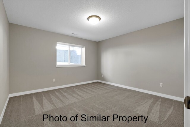 unfurnished room featuring a textured ceiling and carpet floors