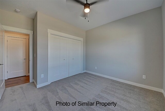 unfurnished bedroom featuring ceiling fan, a closet, and light colored carpet