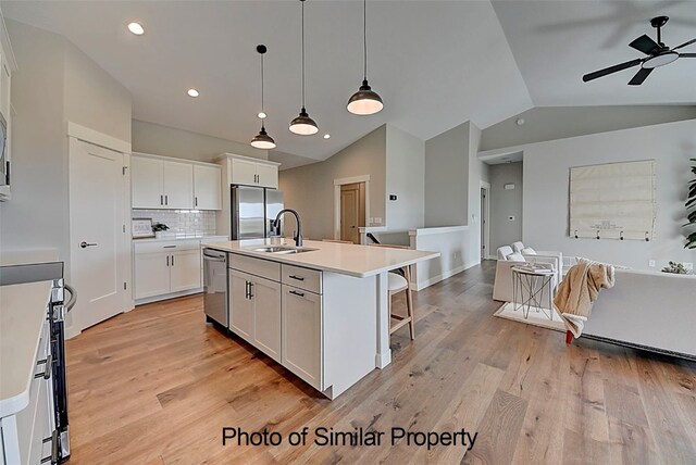 kitchen with light hardwood / wood-style floors, white cabinetry, an island with sink, and stainless steel appliances