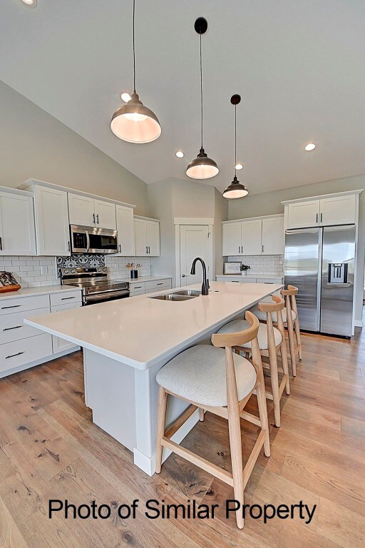 kitchen with sink, white cabinets, stainless steel appliances, and light wood-type flooring