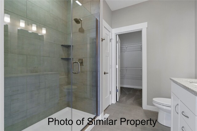 bathroom featuring tile patterned floors, toilet, vanity, and walk in shower