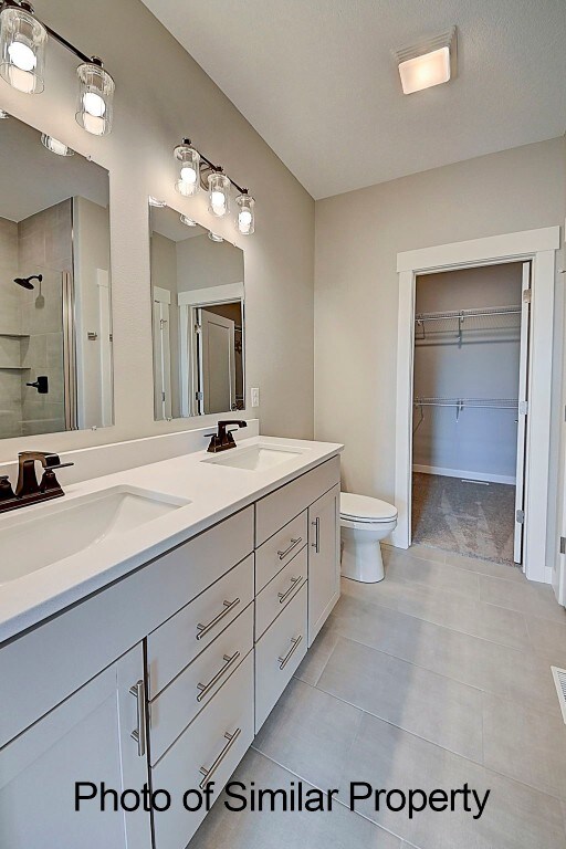 bathroom with toilet, vanity, tile patterned floors, and a shower with shower door