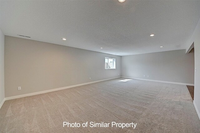 carpeted empty room featuring a textured ceiling