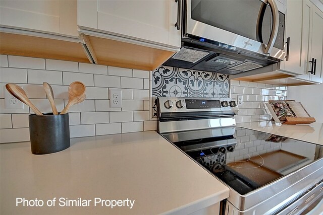 kitchen with white cabinets, decorative backsplash, and appliances with stainless steel finishes