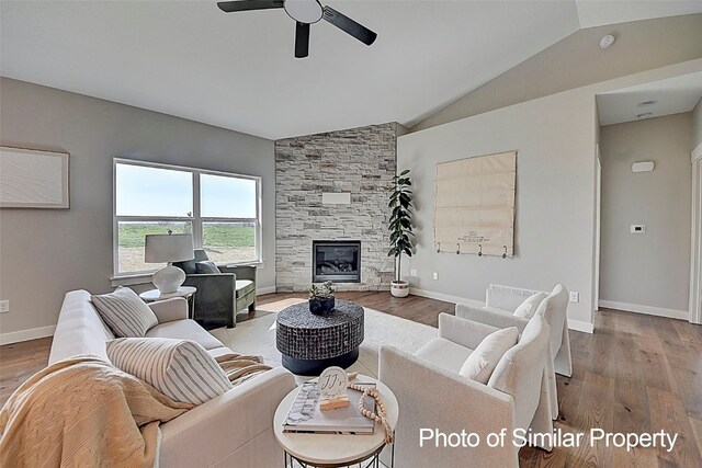 living room with ceiling fan, a fireplace, vaulted ceiling, and hardwood / wood-style flooring