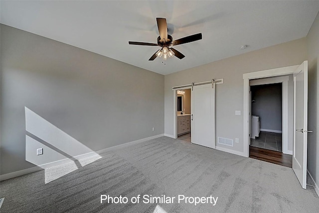 2933 Clubhouse Dr, Marion, IA 52302 - unfurnished bedroom with carpet floors, a barn door, connected bathroom, and a ceiling fan