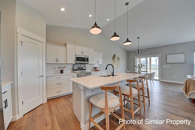 2933 Clubhouse Dr, Marion, IA 52302 - kitchen with stainless steel appliances, light wood-style floors, a center island with sink, decorative backsplash, and a breakfast bar area