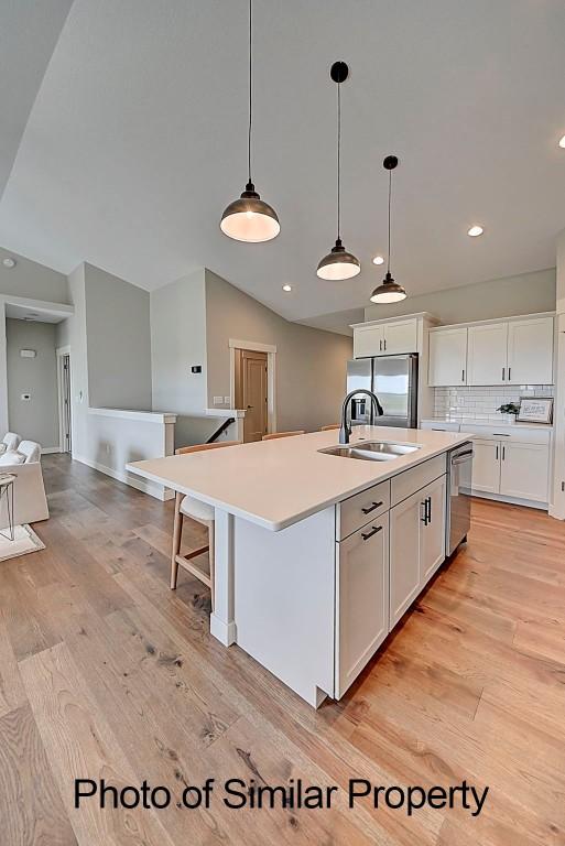 2933 Clubhouse Dr, Marion, IA 52302 - kitchen featuring appliances with stainless steel finishes, white cabinetry, a kitchen island with sink, light countertops, and light wood finished floors