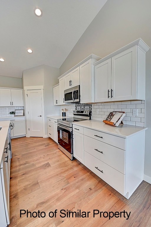 kitchen with white cabinets, stainless steel appliances, and light hardwood / wood-style flooring