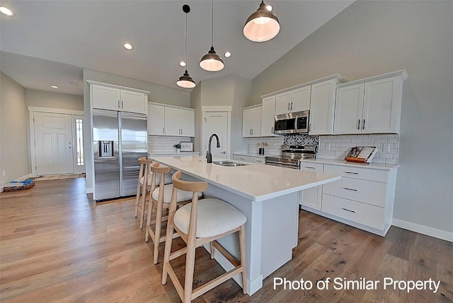 2933 Clubhouse Dr, Marion, IA 52302 - kitchen with appliances with stainless steel finishes, white cabinets, a kitchen island with sink, light countertops, and light wood finished floors