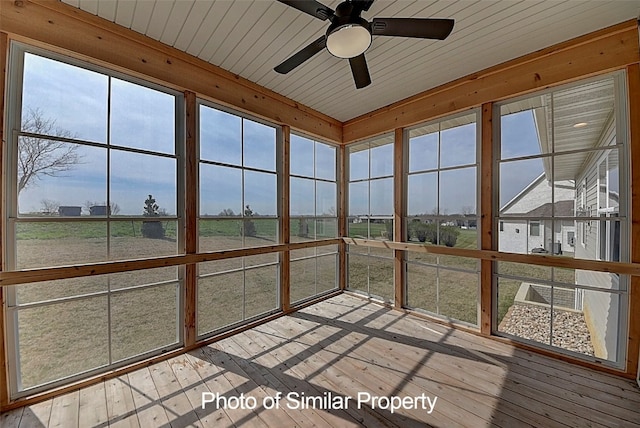 unfurnished sunroom featuring ceiling fan, wooden ceiling, and a wealth of natural light