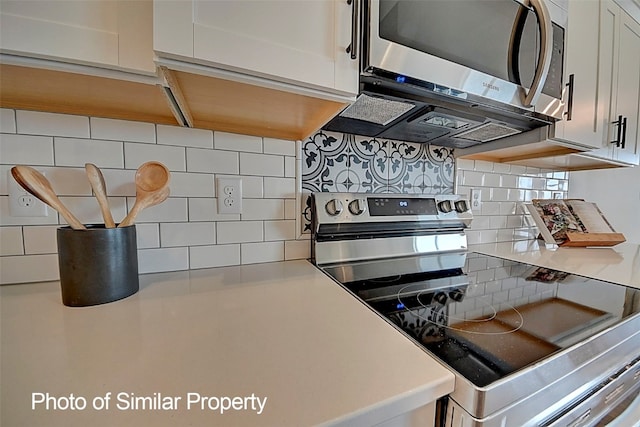 kitchen with decorative backsplash, white cabinetry, and stainless steel appliances